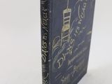 un vieux livre posé sur une table blanche, à côté d'une étiquette rouge