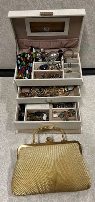 un sac à main en or posé par terre à côté d'un coffret à bijoux