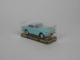 une petite voiture bleue dans une boîte transparente posée sur une surface blanche