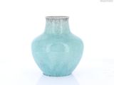 un petit vase bleu posé sur une surface blanche