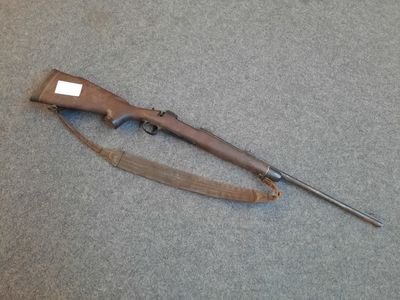 an old rifle is laying on the floor next to a piece of luggage
