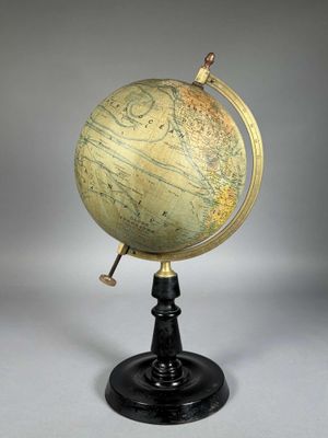 un globe antique posé sur un socle noir, avec un fond blanc