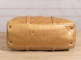 beige quilted leather bag sitting on a wooden table in front of a white wall