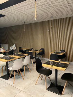 many tables and chairs in this restaurant with a man sitting at the table