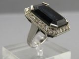 an image of a ring with a black stone surrounded by diamonds