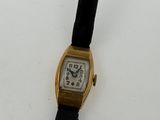 a gold wrist watch with a black band on a white surface