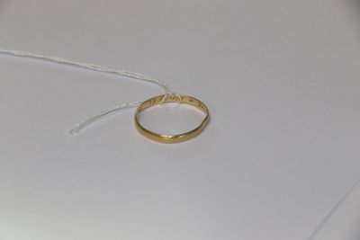 une bague en or posée sur une table blanche, attachée à un fil