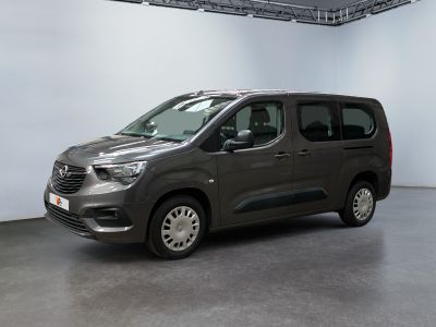 La camionnette grise est garée dans une grande pièce aux murs blancs.