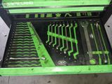 une boîte à outils verte posée par terre, contenant des outils