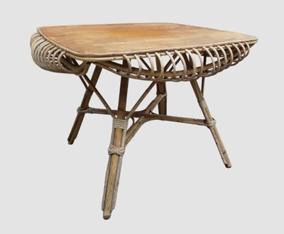 La table est en bois et présente un motif en rotin.
