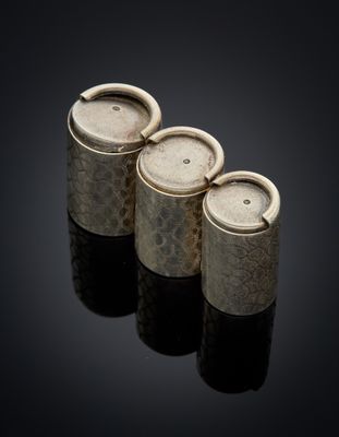 three silver vases sitting on top of a black surface