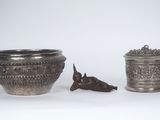 two silver vases sitting next to each other on a white surface