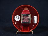 une montre rouge posée sur un objet rouge, sur un fond noir