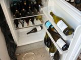 a small refrigerator with many bottles of wine inside of it