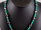 a green and silver beaded necklace on a mannequin mannequin
