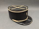 chapeau noir et doré orné d'une croix sur un fond gris