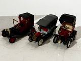 three toy cars sitting next to each other on a white surface