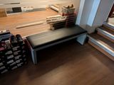 a black bench in the middle of a room next to some stairs