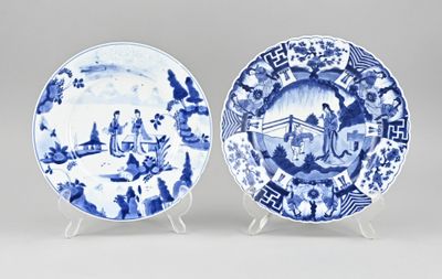 two blue and white plates with figures on them on stands