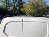 a white van parked in a parking lot with trees in the background
