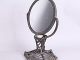 un petit miroir en métal posé sur un support, sur fond blanc