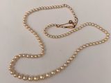 a close up of a pearl necklace on a white surface