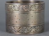 three silver rings with designs on them sitting on a table