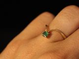 a person ' s hand holding a ring with a green stone on it
