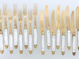 a group of gold and white forks and knives on a white surface