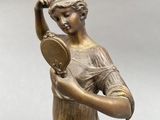 bronze statue of a woman holding a mirror in her hand