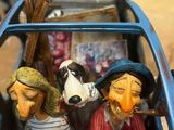 three figurines of people riding in a blue car