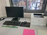 a desk with a computer, printer, mouse, and other items on it