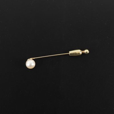 un gros plan sur une broche en or ornée d'une perle