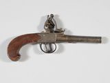 un vieux pistolet surmonté d'un homme, posé sur une surface blanche
