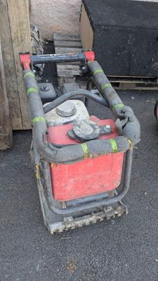 un extincteur rouge et noir posé à côté d'un tas de bois