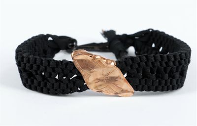 un gros plan d'un bracelet noir orné d'une feuille en cuivre