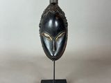 a close up of a black mask on a stand on a white background