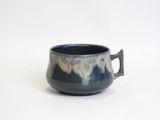 a blue cup with a handle on a white surface