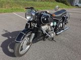a black motorcycle parked in a parking lot next to a grassy hill