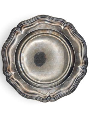 une assiette en argent ancien sur fond blanc, ornée d'un point noir