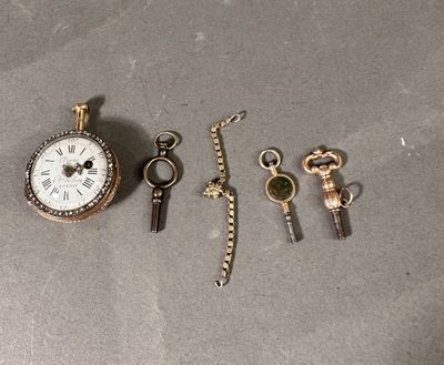 une montre de poche, une clé et un porte-clés posés sur une table