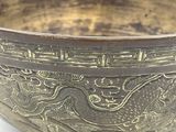 a metal bowl with a design on it on a white surface