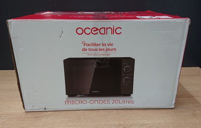 packaging of a black microwave oven sitting on a wooden table