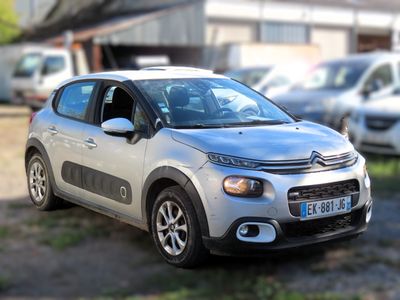 une petite voiture argentée garée devant un immeuble