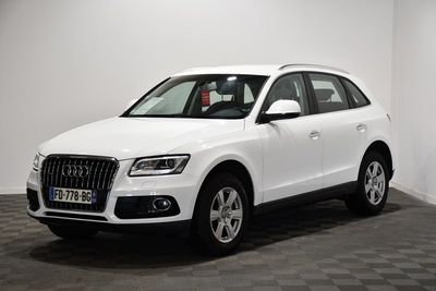 Le SUV Audi blanc est garé dans une pièce au sol carrelé.