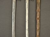 three different types of swords and a knife on a table