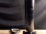 un objet noir posé sur une table en bois, avec une paire de ciseaux à côté