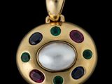 un gros plan d'un pendentif en or orné d'une perle blanche et de pierres multicolores