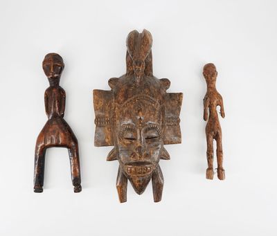 un ensemble de trois masques en bois sculpté sur un fond blanc