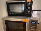 a microwave sitting on top of a counter next to a cup